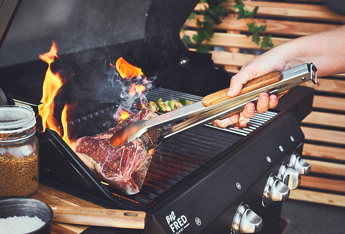 Grillszene Steack wird auf dem Grillrost gewendet Grillszene Steack wird auf dem Grillrost gewendet