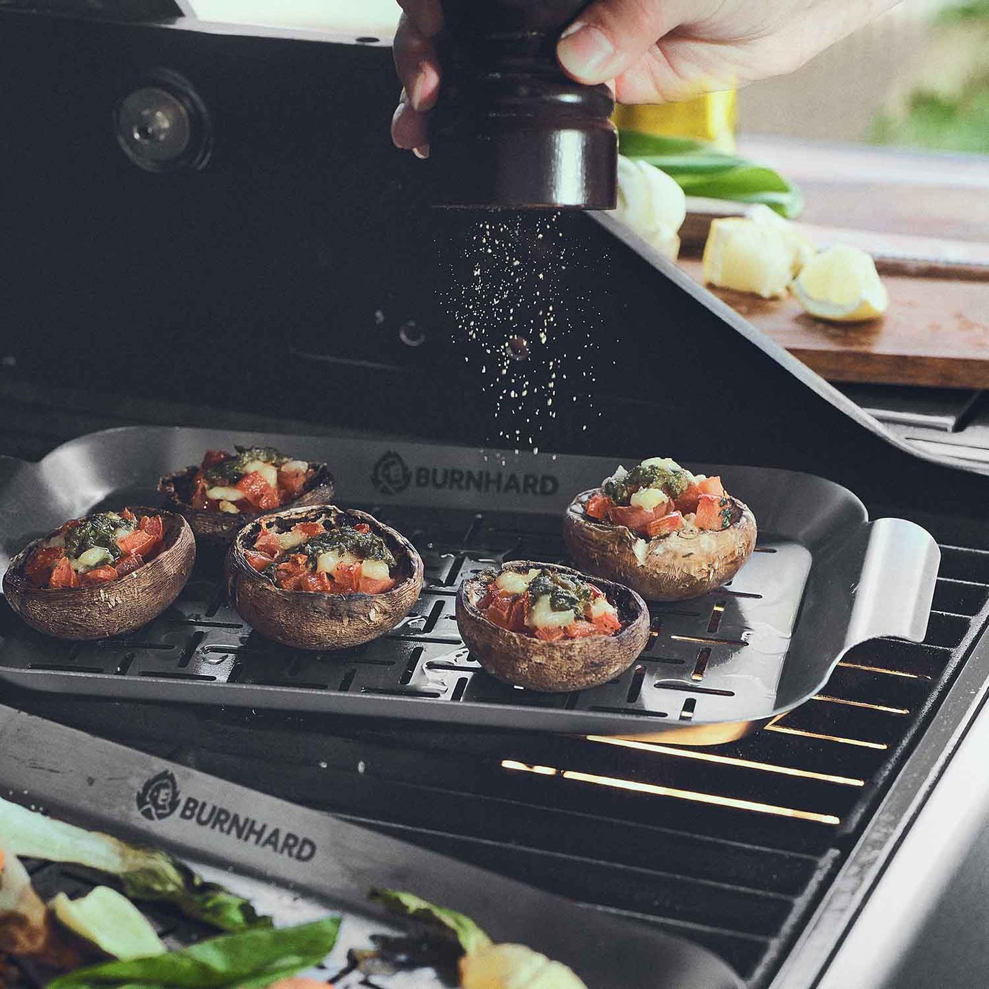 Grillszene gefüllte Pilze werden in Grillschale liegend gesalzen Grillszene gefüllte Pilze werden in Grillschale liegend gesalzen