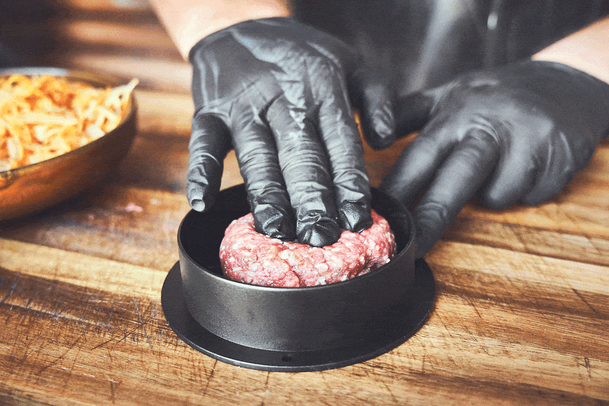 Patties werden mit Käse in der Burgerpresse zubereitet Patties werden mit Käse in der Burgerpresse zubereitet