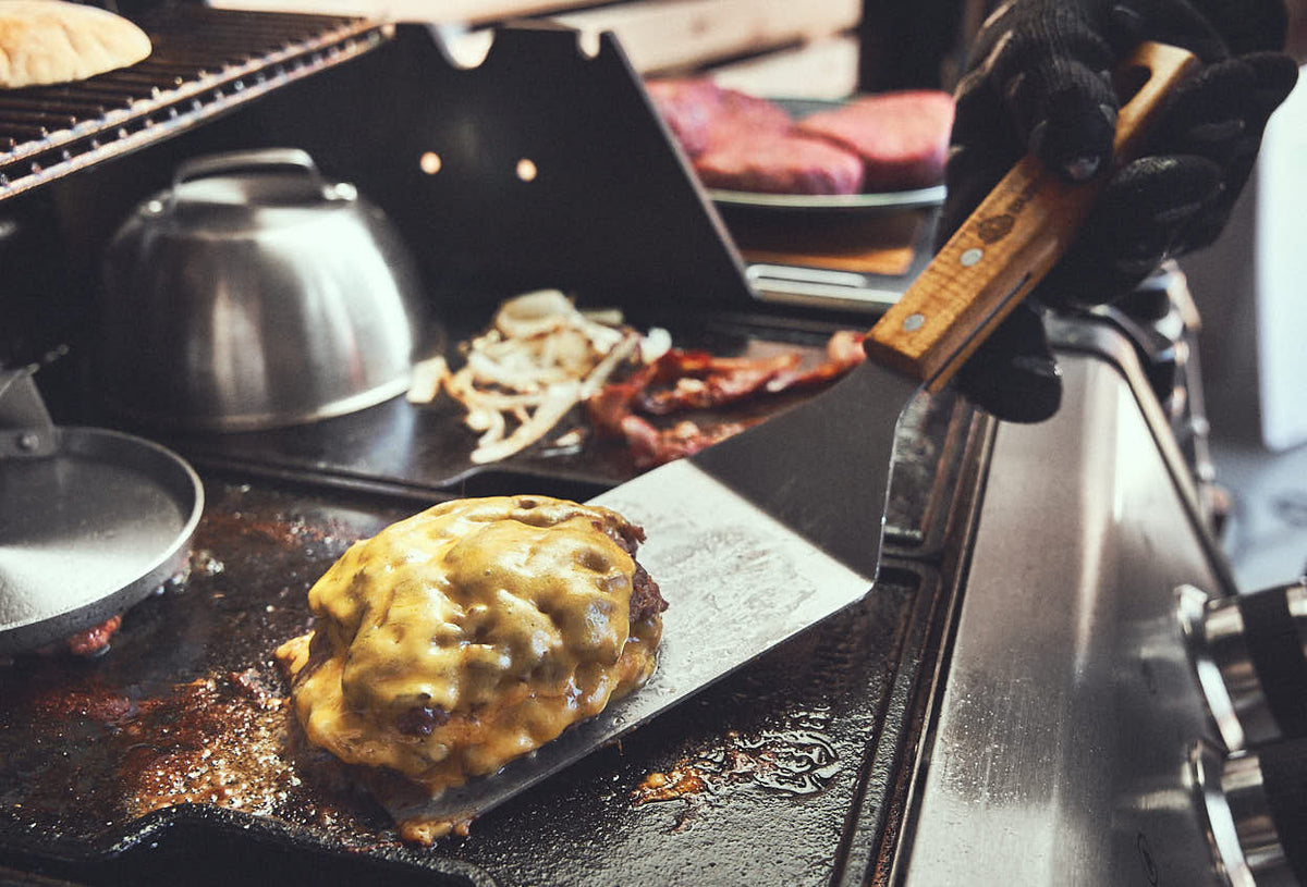 Grillszene fertiger Patty wird mit Scraper vom Grill genommen Grillszene fertiger Patty wird mit Scraper vom Grill genommen