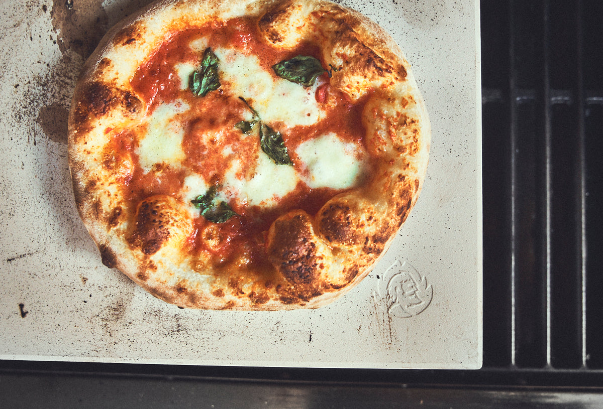 Grillszene Pizza wird auf Pizzastein auf dem Grill gebacken Grillszene Pizza wird auf Pizzastein auf dem Grill gebacken
