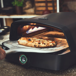 Image 40250747093307 Szene fertig gebackene Pizza wird aus dem Pizzaofen geholt.
