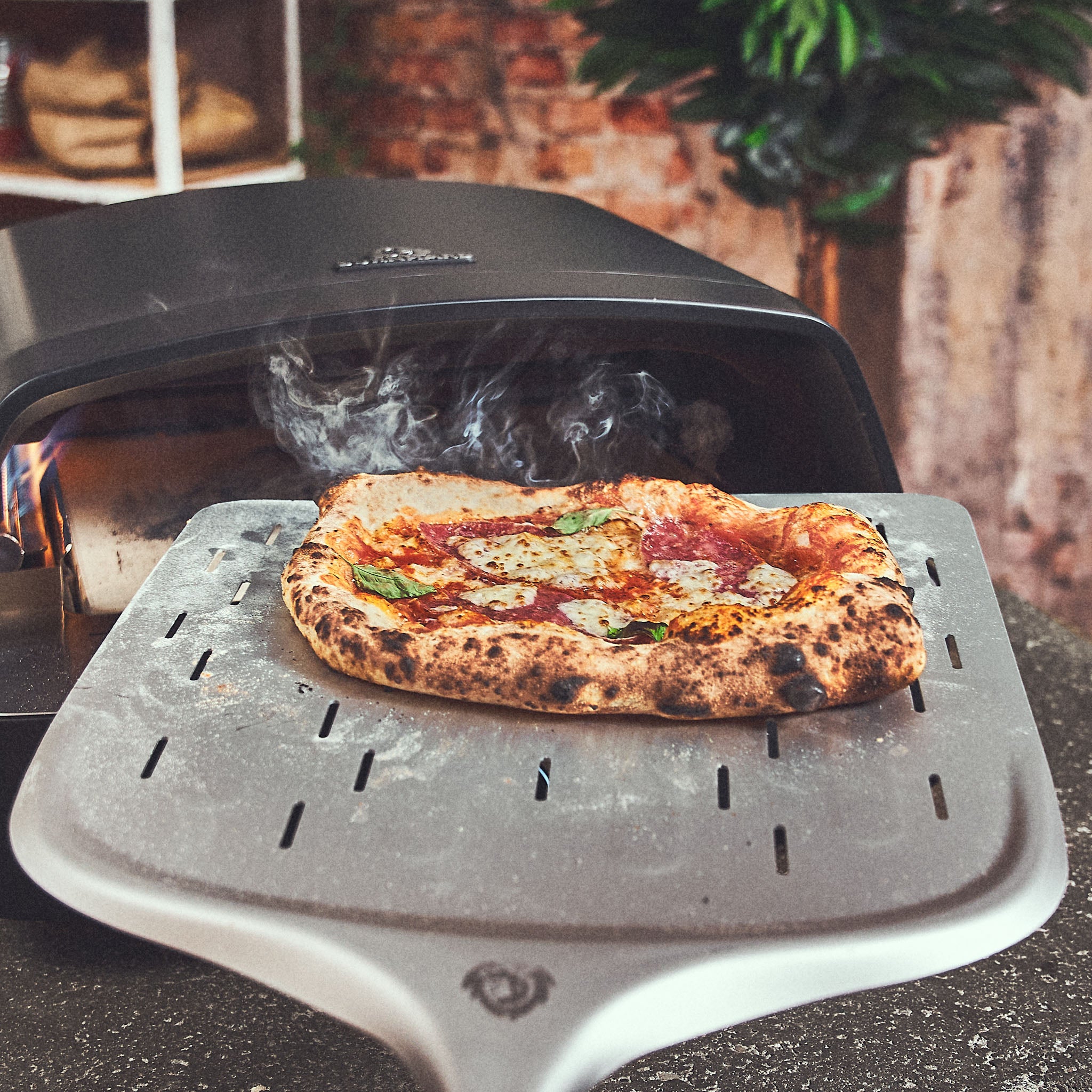 Fertig gebackene Pizza wird aus dem Ofen geholt Fertig gebackene Pizza wird aus dem Ofen geholt