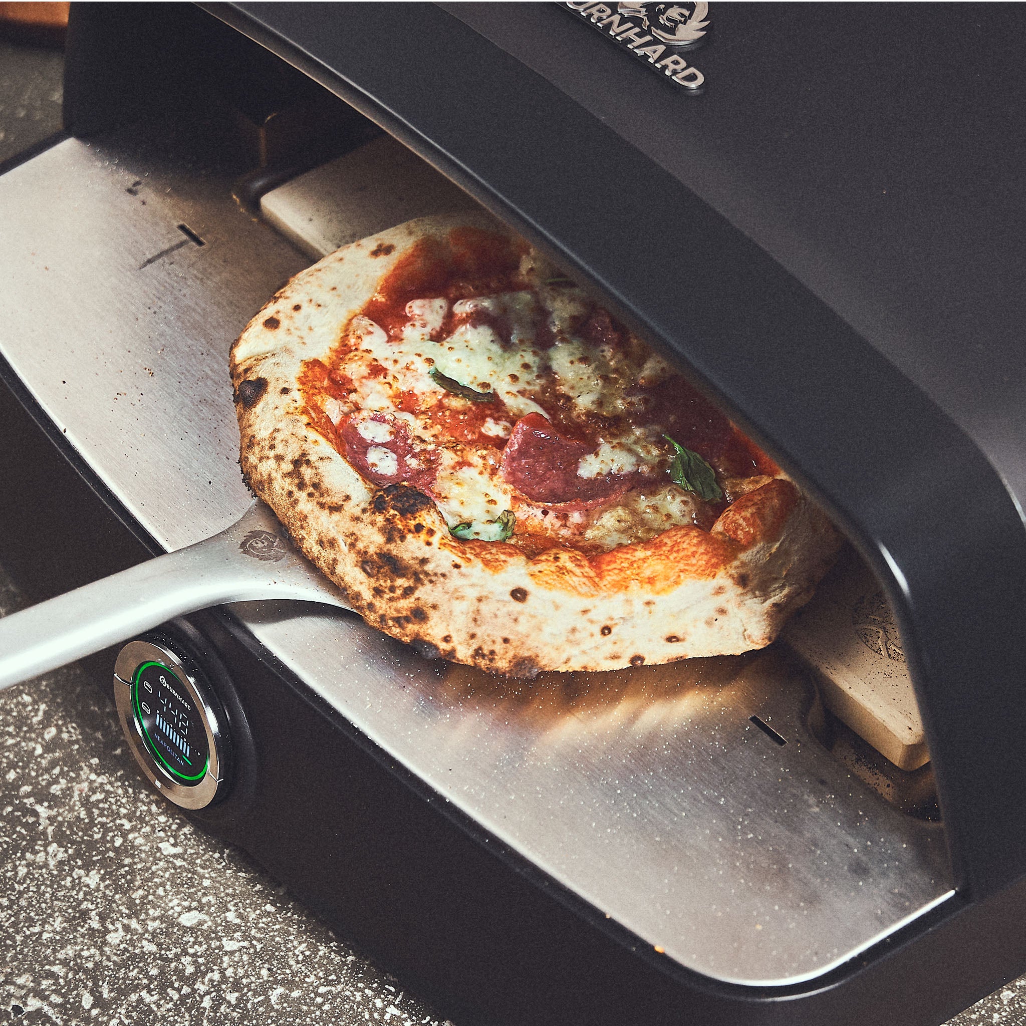 Pizza wird mithilfe des extra langen Einschub-Bereichs aus dem Ofen gezogen Pizza wird mithilfe des extra langen Einschub-Bereichs aus dem Ofen gezogen