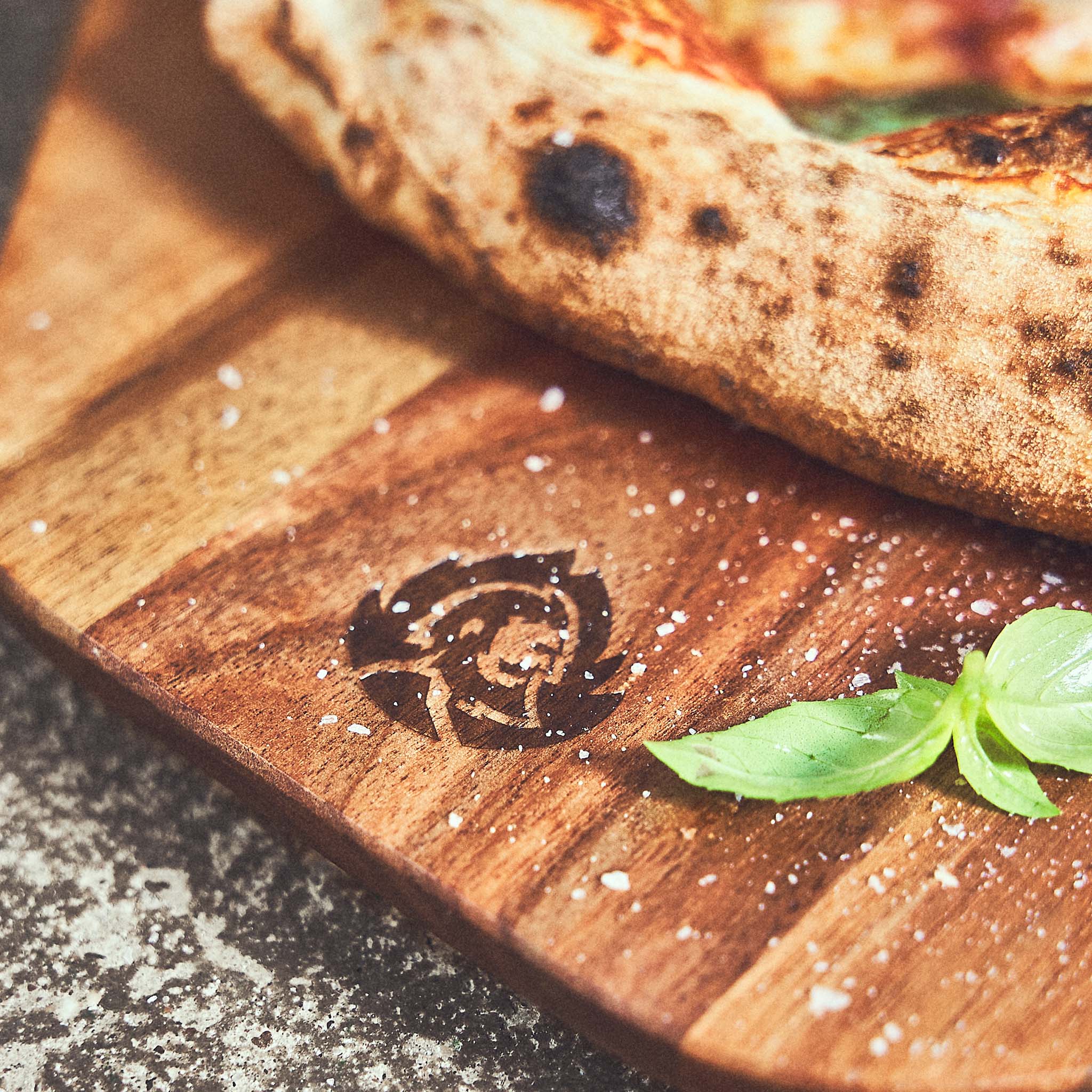 Pizzabrett aus Akazienhol mit BURNHARD Bildmarke eingraviert und fertiger Pizza Pizzabrett aus Akazienhol mit BURNHARD Bildmarke eingraviert und fertiger Pizza