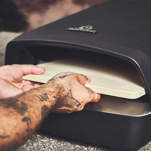 Pizzastein wird in den Ofen eingesetzt Pizzastein wird in den Ofen eingesetzt