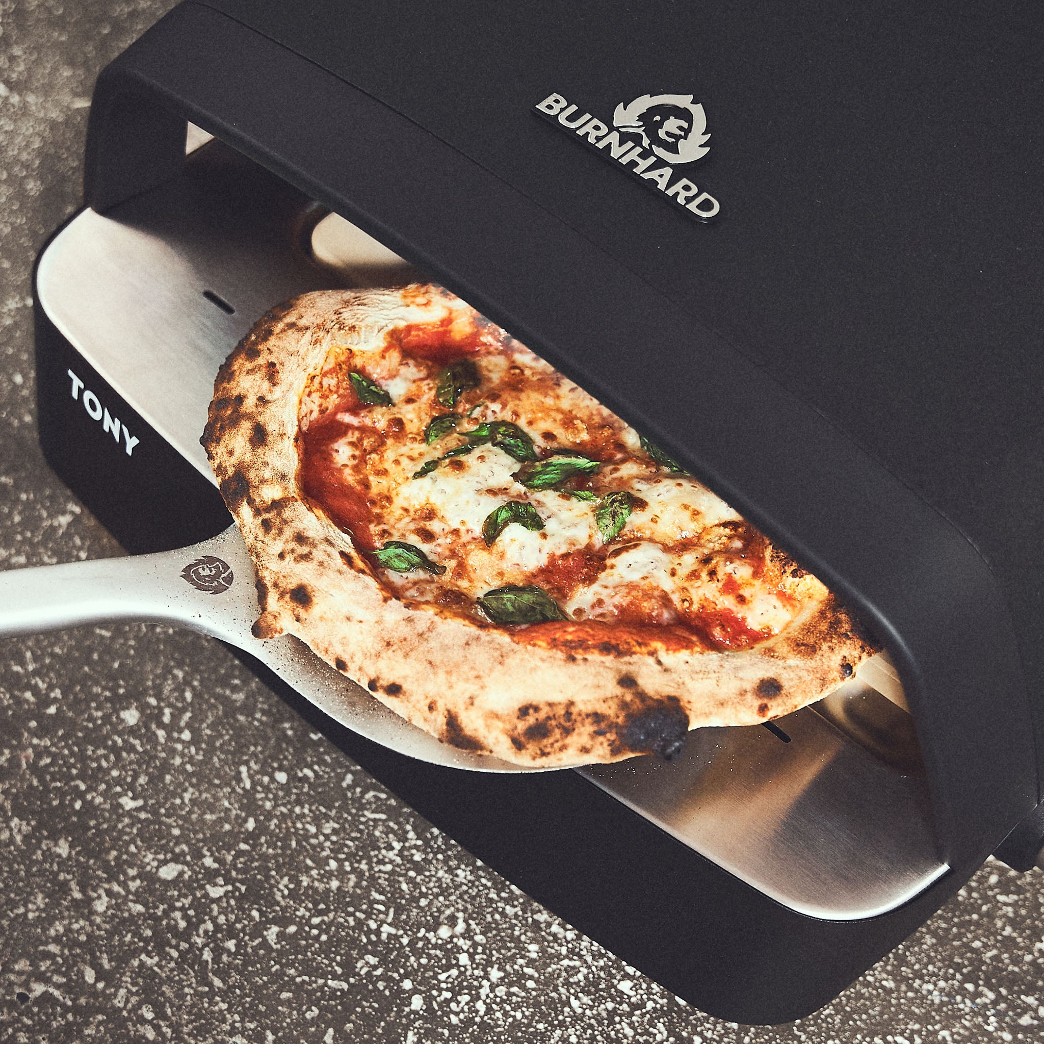 Fertig gebackene Pizza wird dem Ofen entnommen + 946480 Fertig gebackene Pizza wird dem Ofen entnommen + 946480