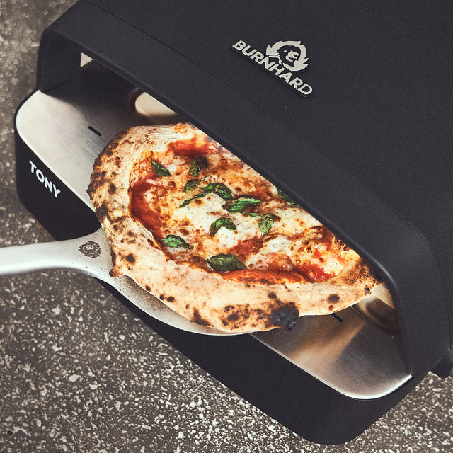 Fertig gebackene Pizza wird dem Ofen entnommen + 946480  Fertig gebackene Pizza wird dem Ofen entnommen + 946480