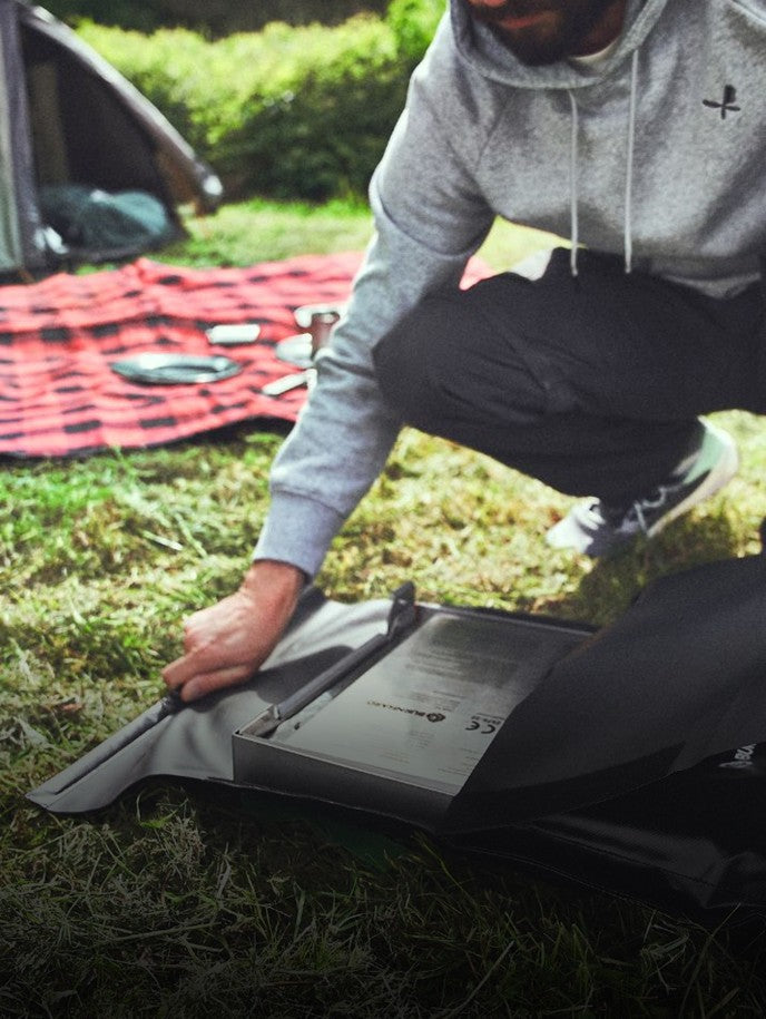Campinggrill JONES wird auf einer Wiese zusammengeklappt aus seiner passenden Tasche ausgepackt