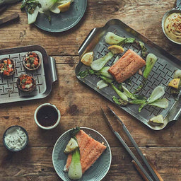 943623_943624 Draufsicht Tischszene mit Fisch und Beilagen auf Edelstahl Grillschale serviert