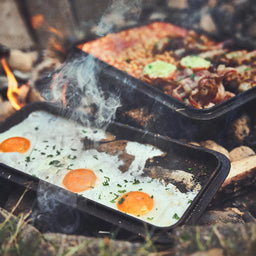 944205_944206_Lagerfeuerszene Spiegeleier braten im Deckel sowie Bohnen, Bacon und Wurst in der Kastenform