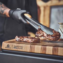 Grillszene Steaks werden auf dem Holzbrett abgelegt
