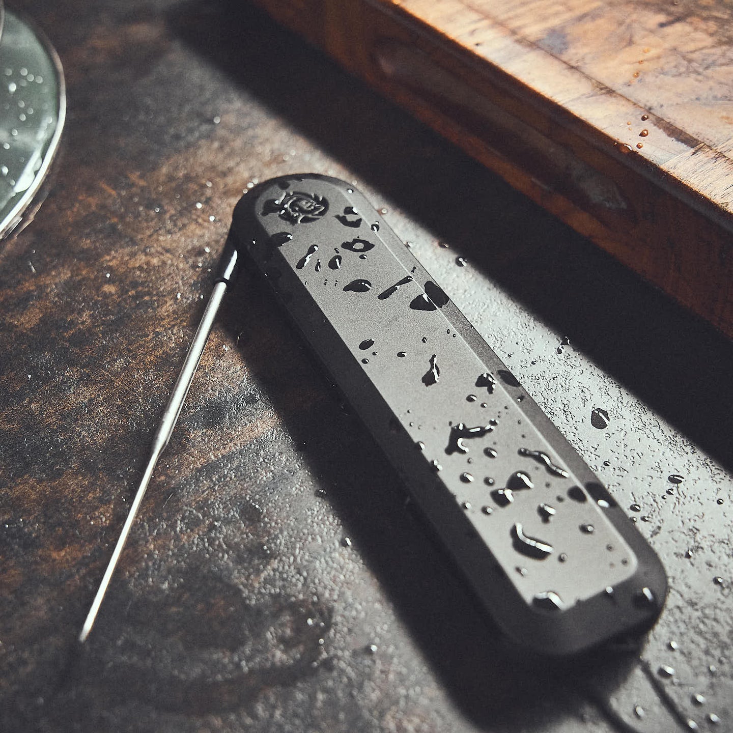 Einstich-Thermometer auf Holztisch mit Spritzwassertropfen