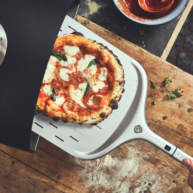 Pizza wird auf Pizzaschieber in den Ofen gegeben