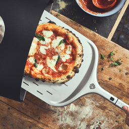 944651 Pizza wird auf Pizzaschieber in den Ofen gegeben