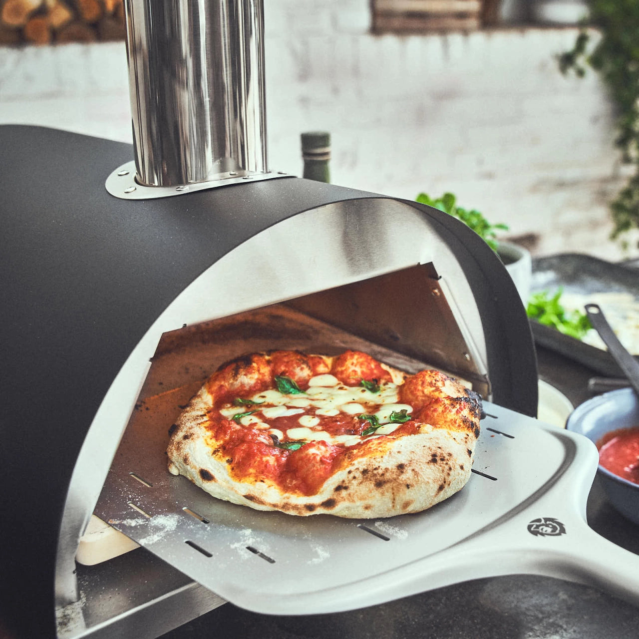 Fertig gebackene Pizza wird mit dem Pizzaschieber aus dem Ofen entnommen