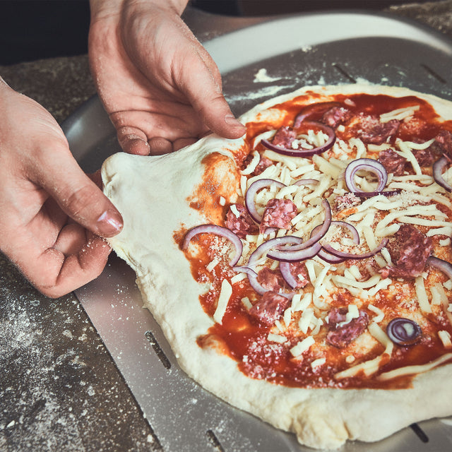 946052 Pizza wird auf dem Pizzaschieber 14 Zoll größer gezogen