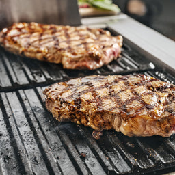 Steak mit Grillstreifen wird auf der geriffelten Seite gegrillt mit Gusseisen Grillplatte 2-in-1 für modularen Gasgrill GRANT 