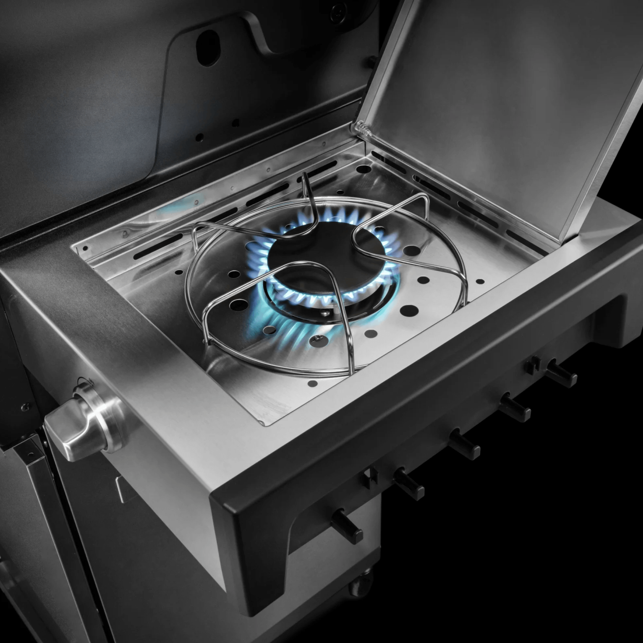 Seitenkochfeld in Edelstahl des BURNHARD FRED Series 4 mit geöffneter Abdeckung und aktiver Gasflamme in Nahaufnahme 946773