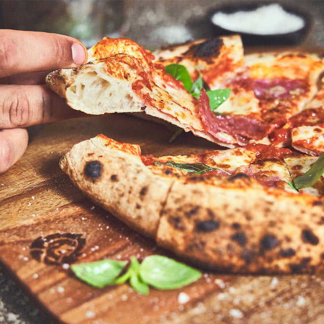 Pizzastück wird vom Akazienholz Pizzabrett genommen