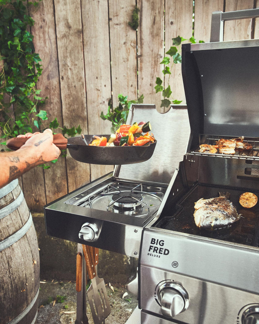 Pfanne und Grillbesteck in Benutzung an einem FRED Gasgrill.